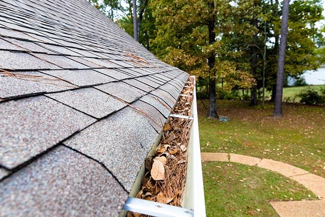 close-up of hand scooping leaves out of gutters